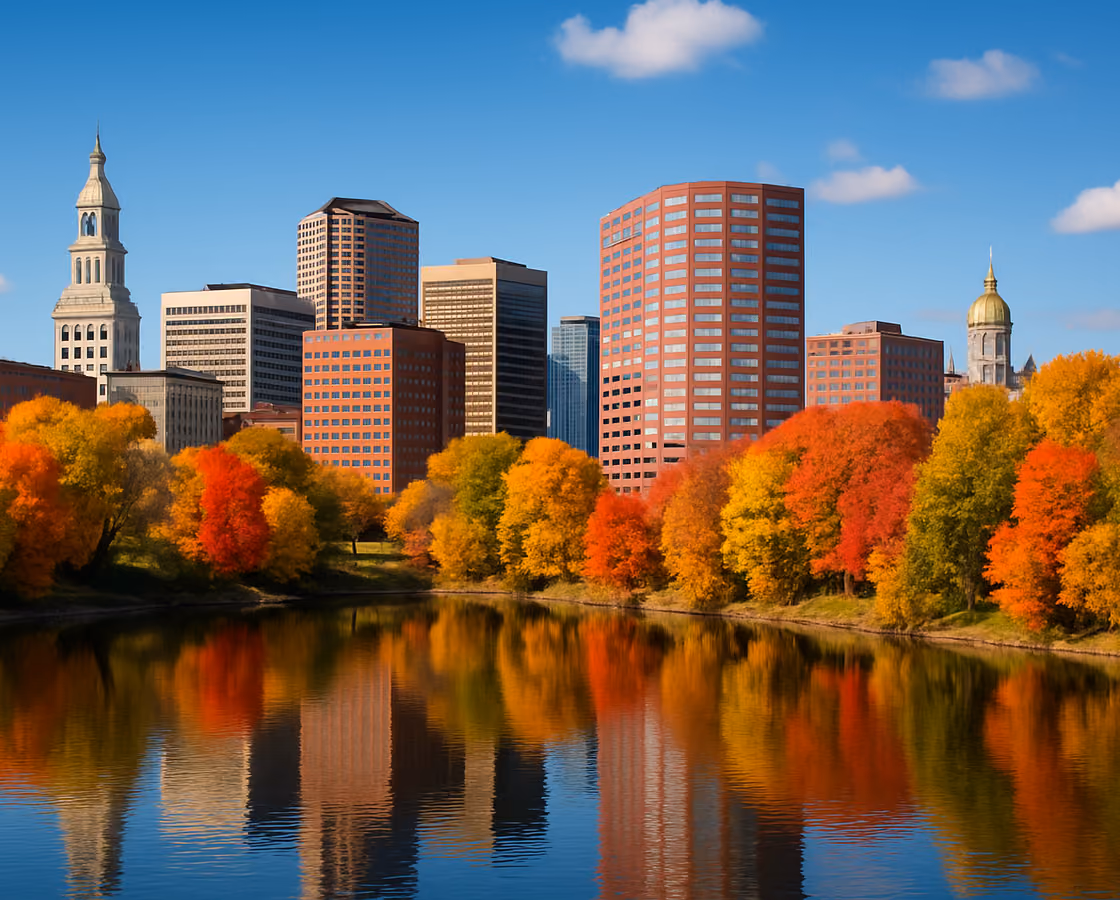 Hartford, Connecticut skyline across the Connecticut River with the Travelers Tower and the gold-domed State Capitol among autumn trees